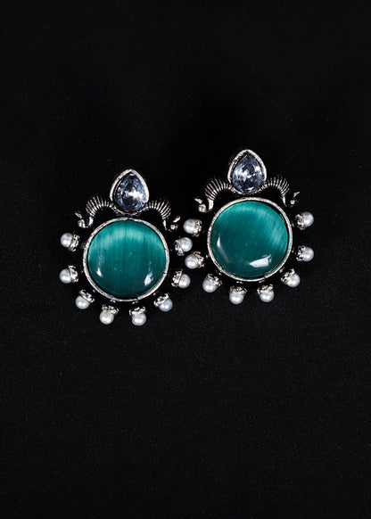 A pair of silver-toned stud earrings featuring oval green cat's eye stones, surrounded by small clear rhinestones and a teardrop-shaped clear stone at the top