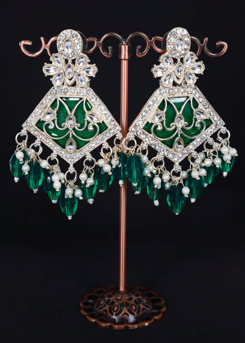 A pair of ornate gold-plated dangle earrings with green enamel panels, clear rhinestone embellishments, and dangling green crystal beads.