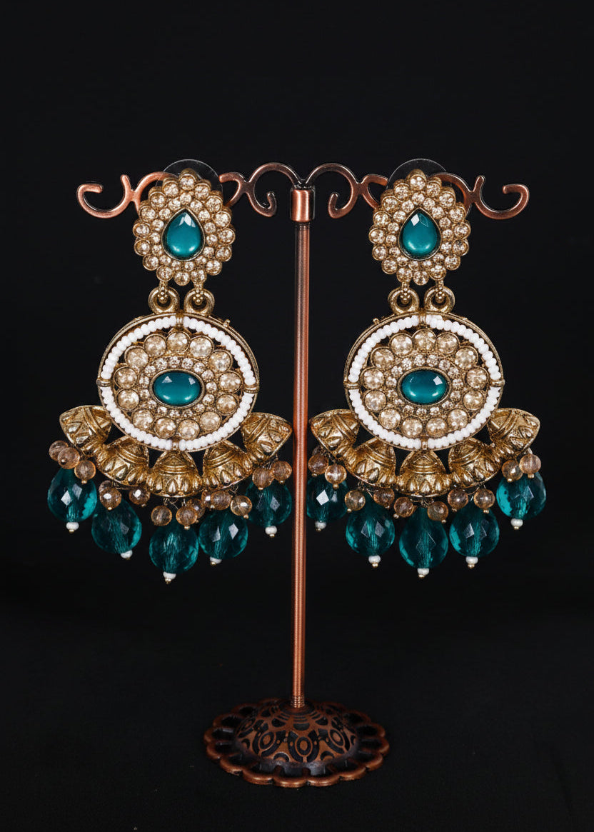 A pair of ornate gold-toned statement earrings. The earrings feature turquoise blue teardrop stones, white pearl-like circular details, and dangling faceted turquoise beads.
