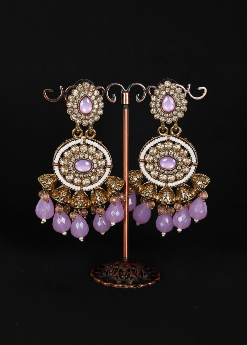 A pair of ornate gold-toned chandelier earrings with light lilac stones and white pearl-like accents.