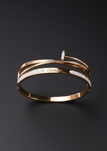 A gold-tone Cartier bangle bracelet with pavé-set clear stones, displayed on a black velvet jewelry box against a dark background.