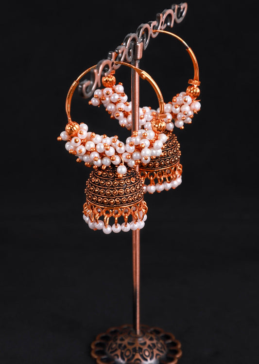 A pair of traditional Indian jhumka earrings with gold-toned metalwork, white pearl beadwork, and dangling tassel details